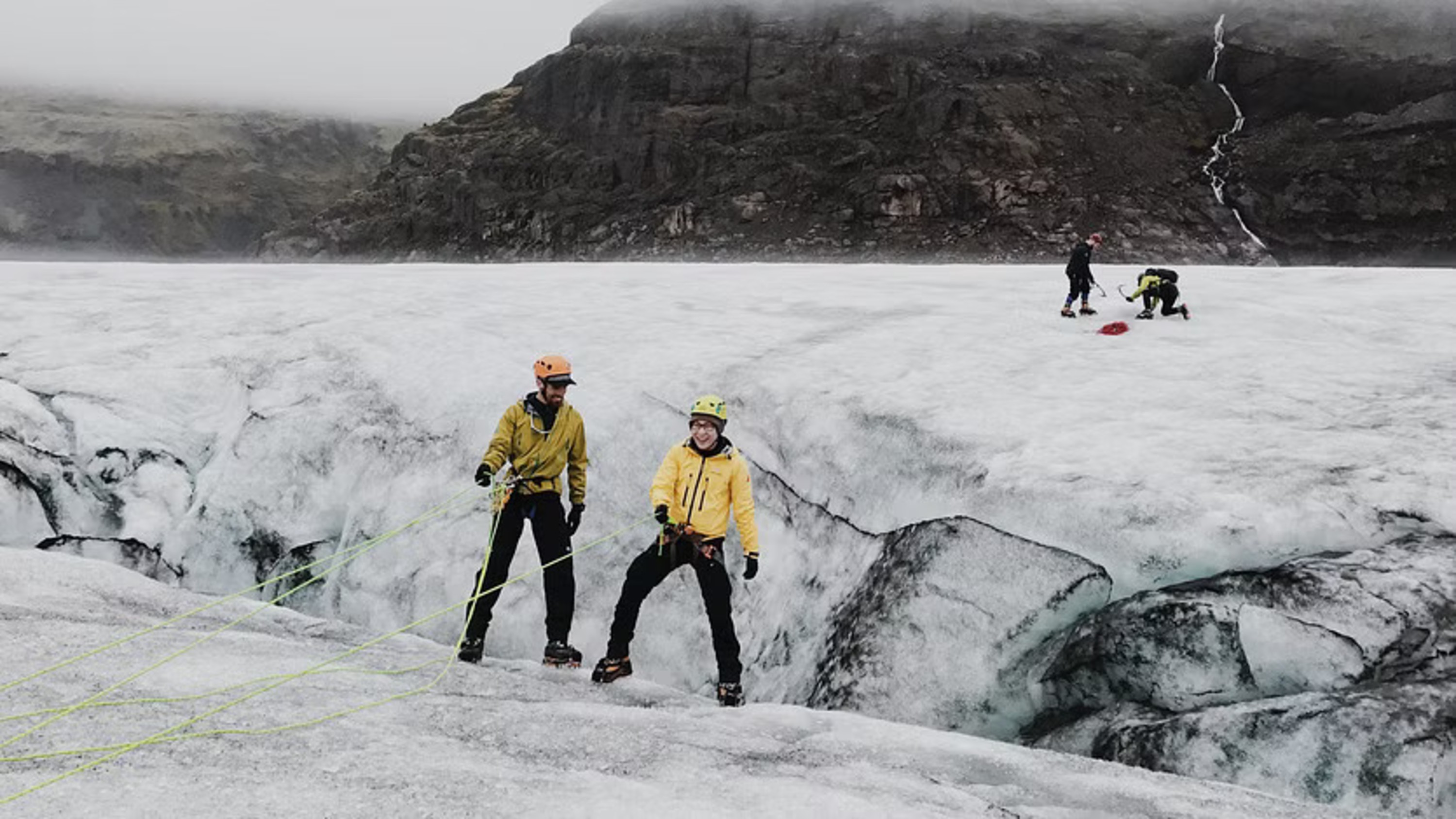 Hikers standing on a glacier, surrounded by crevasses and ice-covered peaks