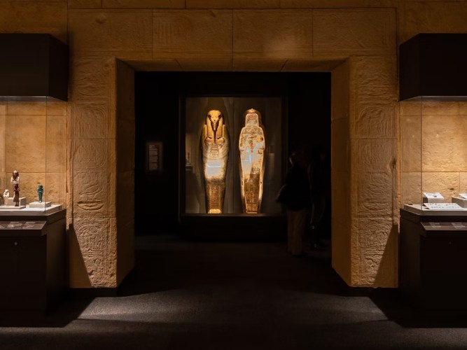 在引人注目的燈光下，展示著帶有象形文字和木乃伊遺骸的古埃及石棺