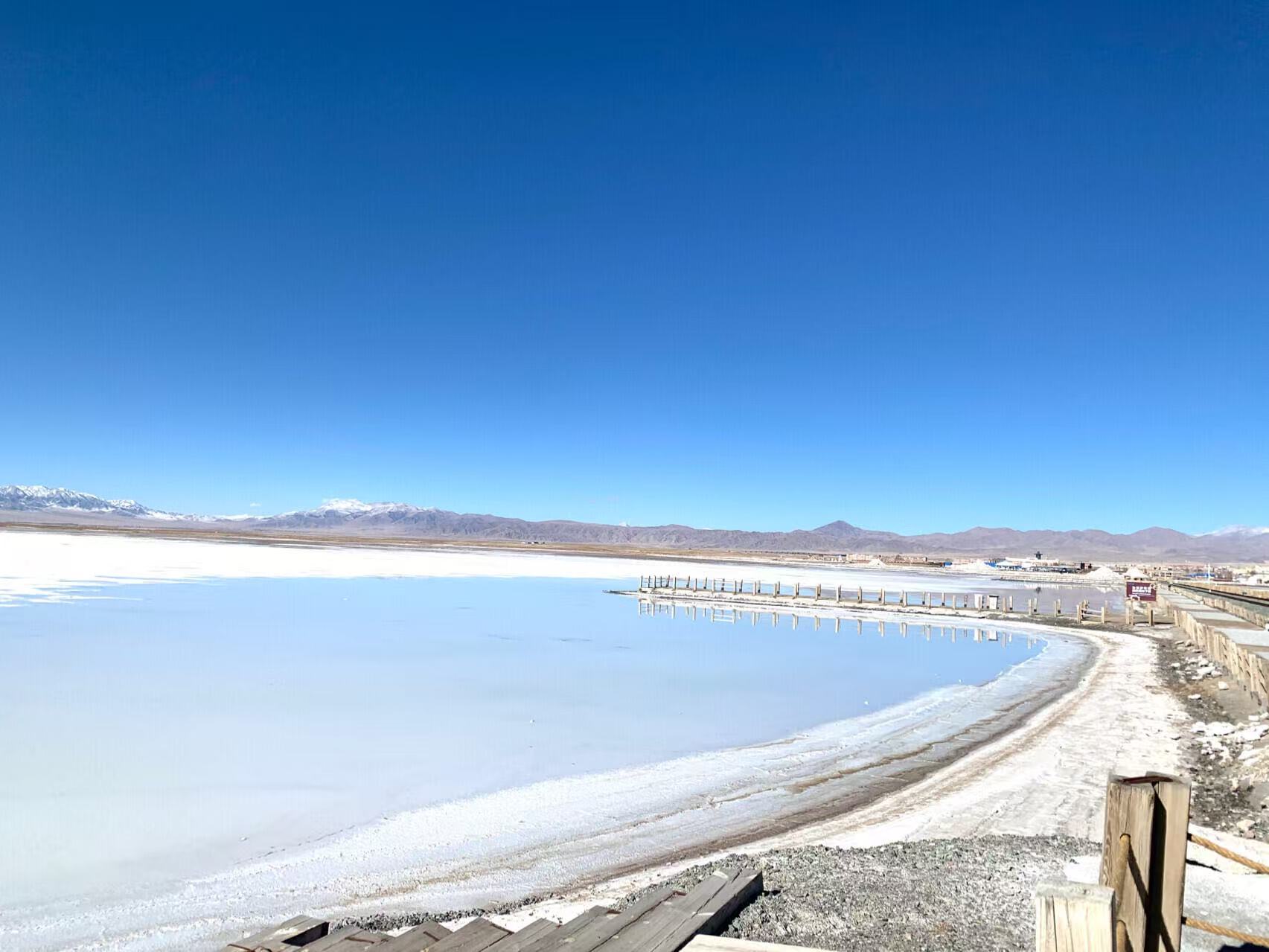 湛藍晴空下，鹽湖如鏡面一般，木棧道沿著湖岸蜿蜒，鹽白大地倒映遠山，乾淨純粹，是天空之鏡獨有的浪漫