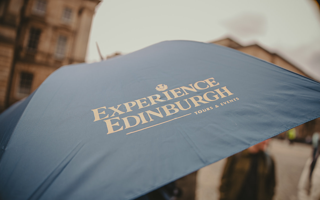 藍色雨傘，印有「Experience Edinburgh」品牌標誌，在城市導覽行程中使用