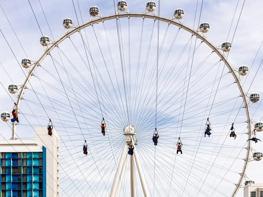 High Roller observation wheel in background as zipline riders glide toward it