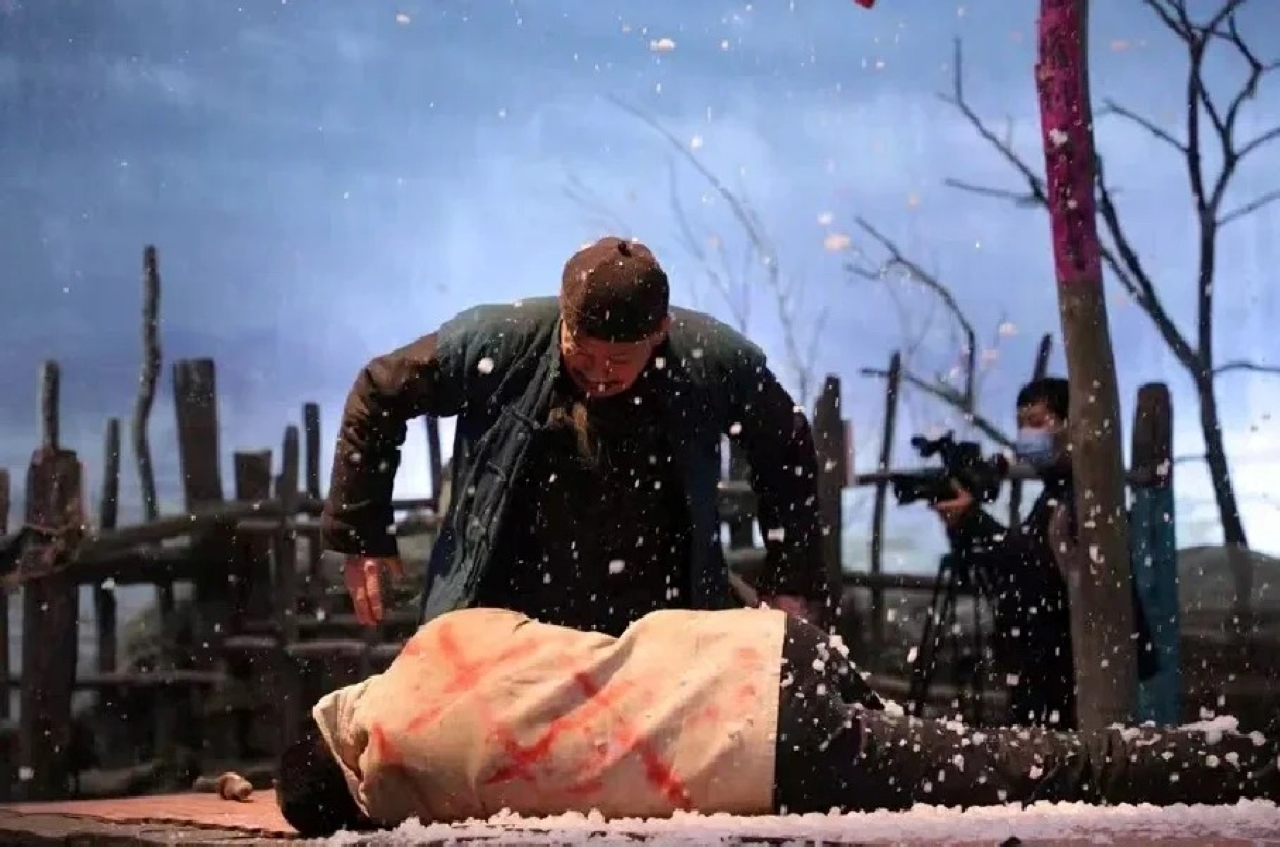 以雪地為場景,營造出肅殺、悲情的氛圍。畫面中一人俯身於倒地染血的另一人旁,雪花紛飛,搭配簡陋的木柵欄背景,老人跪地與飄雪營造壓抑氛圍,演繹原著裡的悲情情節 以雪地為場景,營造出肅殺、悲情的氛圍。畫面中一人俯身於倒地染血的另一人旁,雪花紛飛,搭配簡陋的木柵欄背景,老人跪地與飄雪營造壓抑氛圍,演繹原著裡的悲情情節