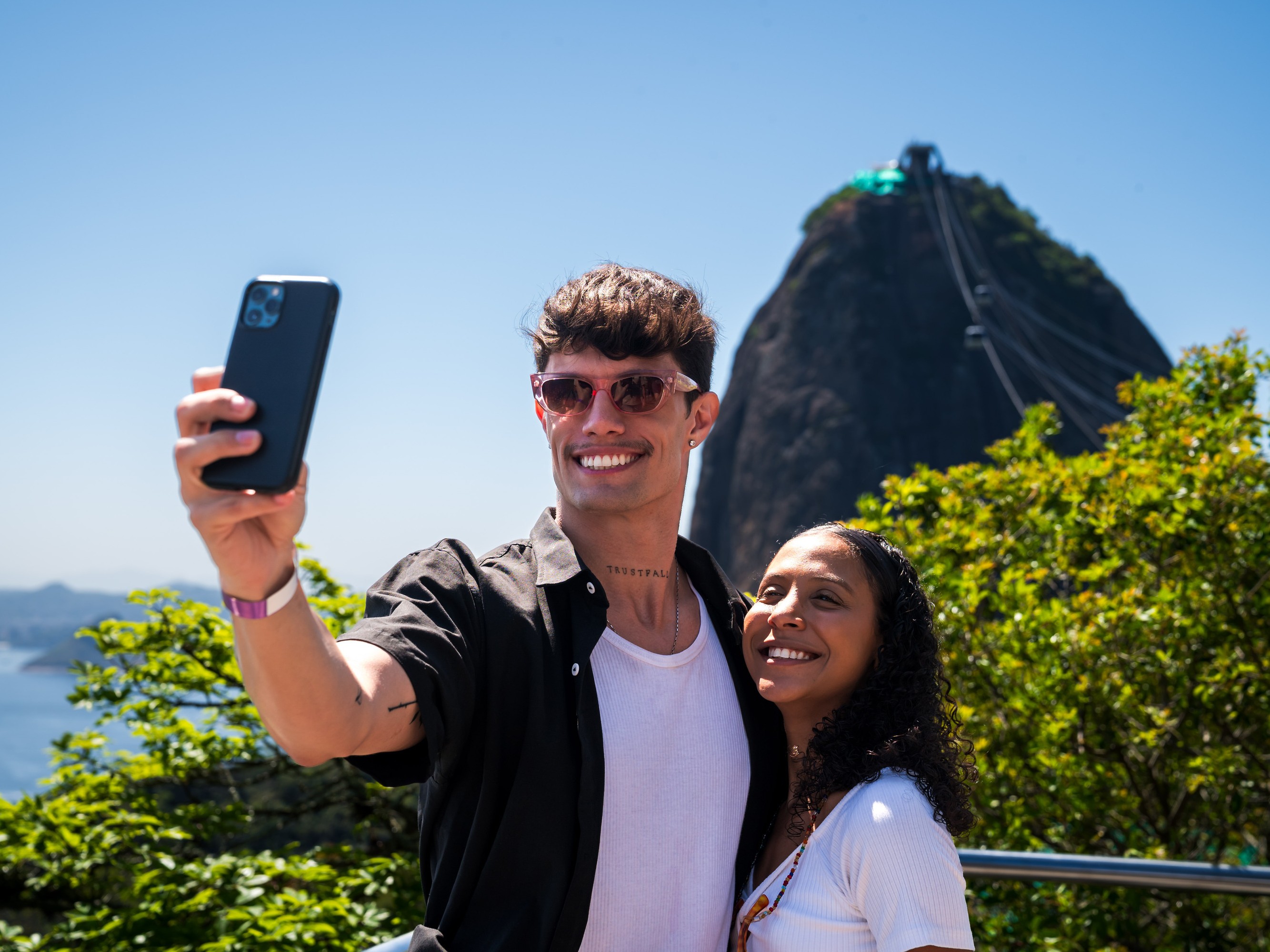 Tourists taking selfies on Corcovado’s viewpoint with city and ocean in the background