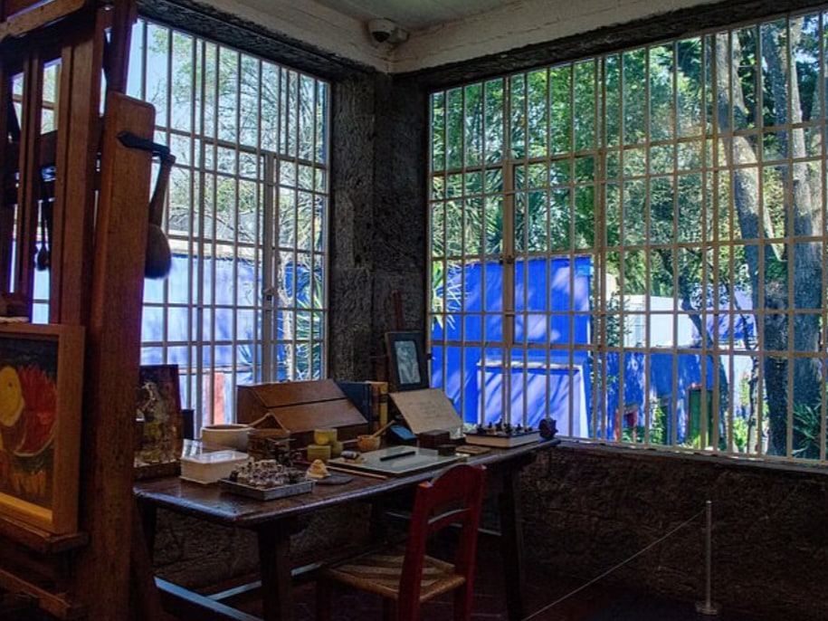 Guided group admiring personal belongings inside Frida Kahlo Museum, gaining insight into her artistic life.