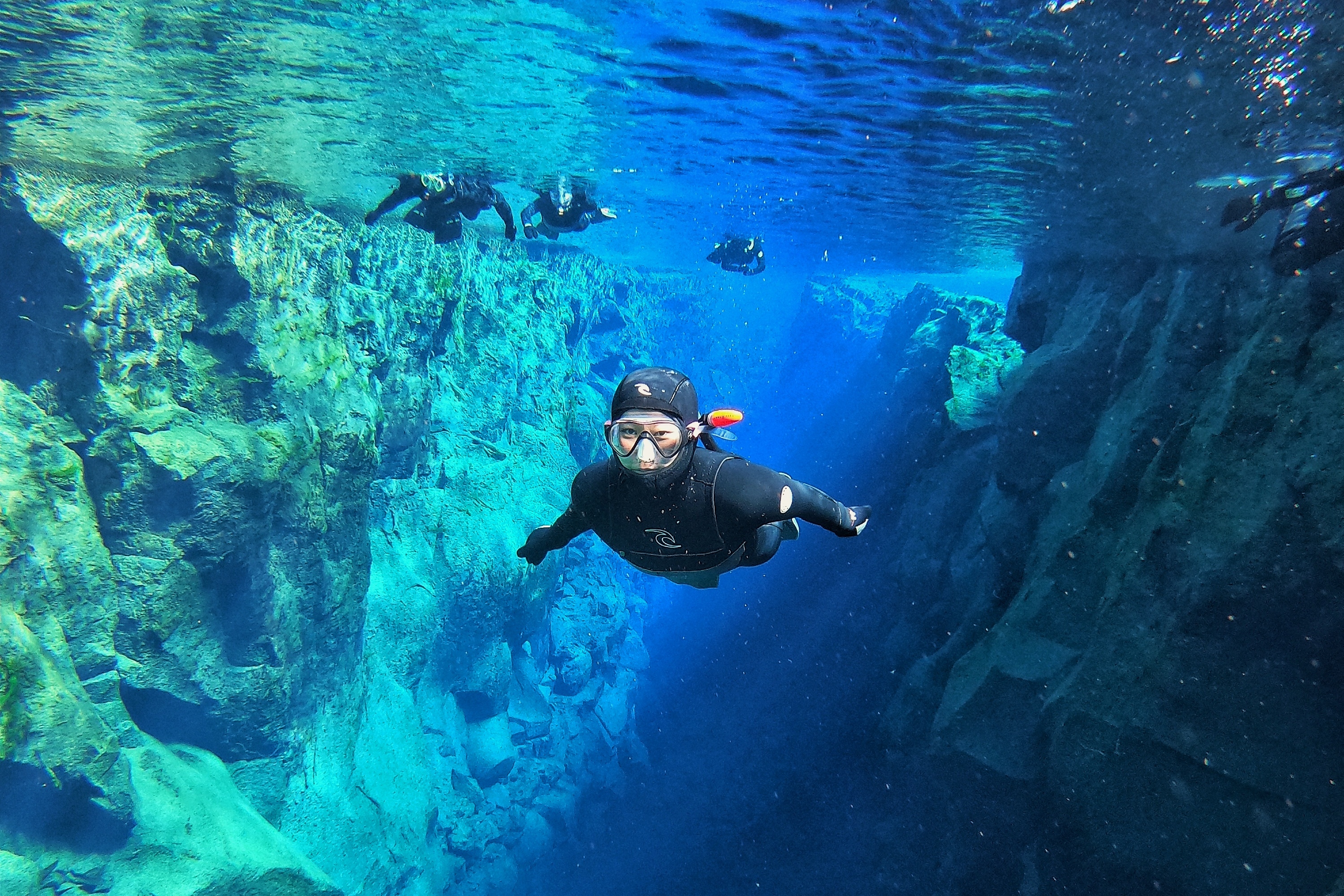 a woman snorkeling in the blue waters of silfra