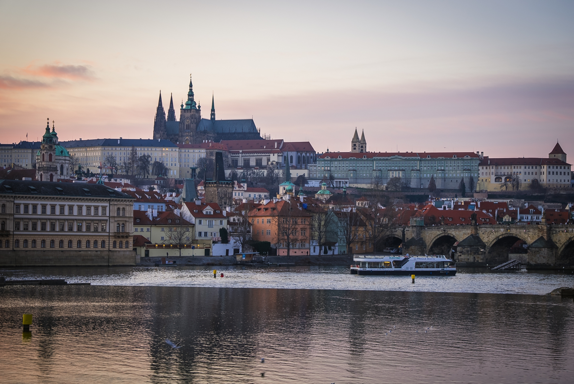 欣賞粉紅色的日落天空,其倒影在伏爾塔瓦河平靜的水面上閃爍 欣賞粉紅色的日落天空,其倒影在伏爾塔瓦河平靜的水面上閃爍