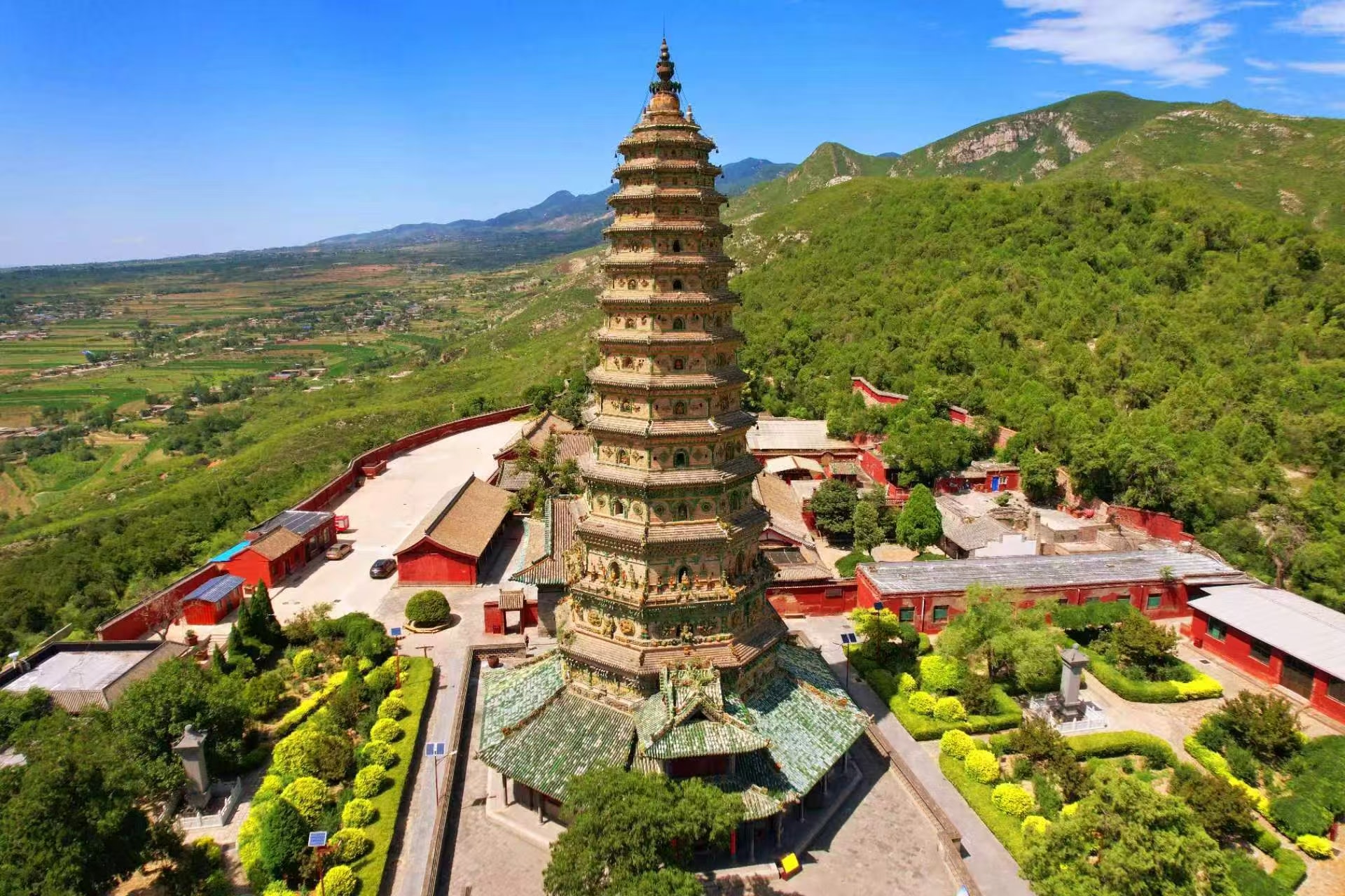 廣勝寺標誌性飛虹塔矗立山間，通體琉璃層疊精巧，塔身十三層錯落有致。紅牆古殿環繞，四周青山連綿、田野鋪展，晴空之下盡顯這座明代琉璃塔恢弘古樸的風貌