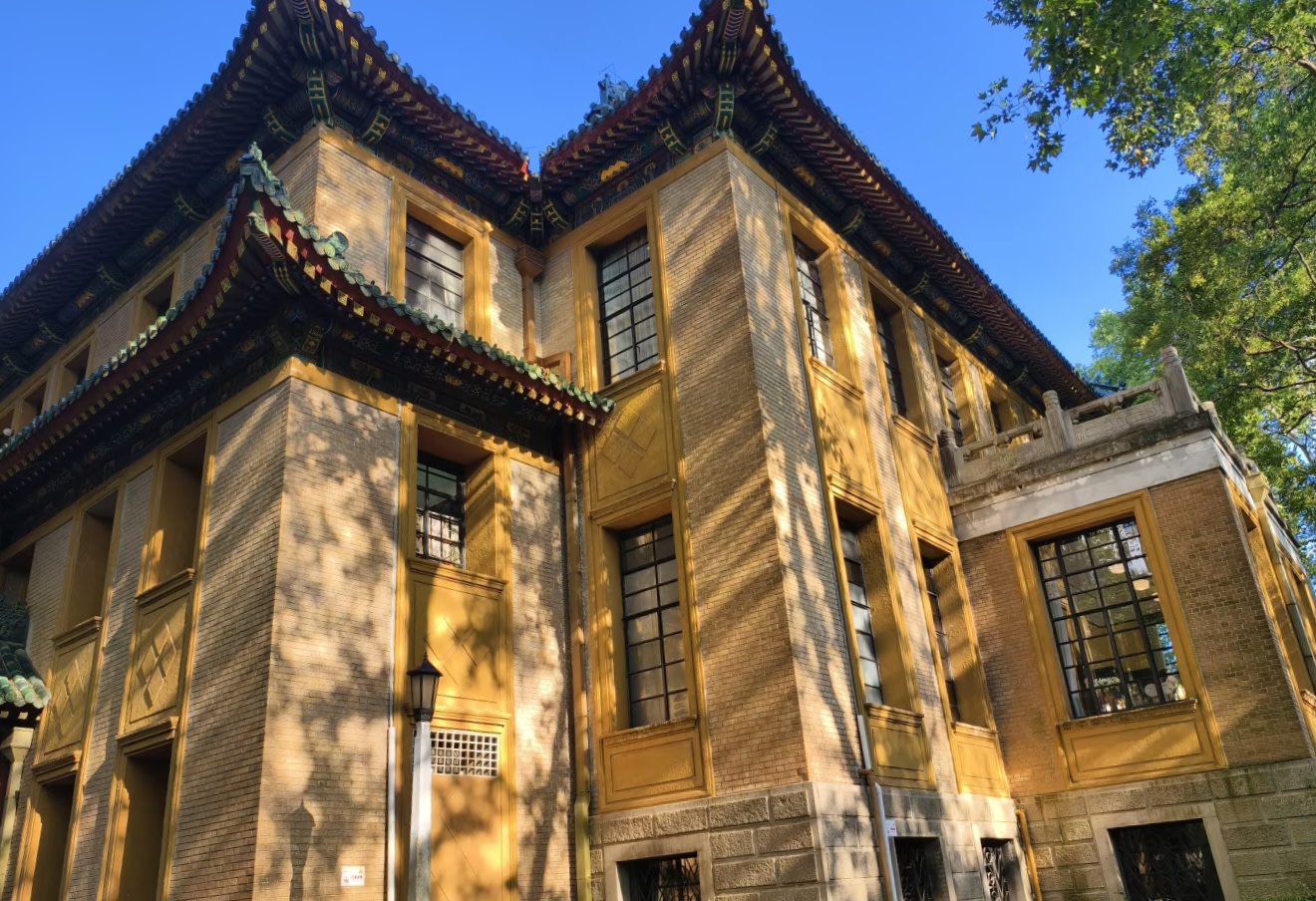 藍天下,黃牆黛瓦的建築靜靜佇立,飛簷翹角綴著綠釉瓦當,中西合璧的窗欞在樹影裡明暗交錯 藍天下,黃牆黛瓦的建築靜靜佇立,飛簷翹角綴著綠釉瓦當,中西合璧的窗欞在樹影裡明暗交錯