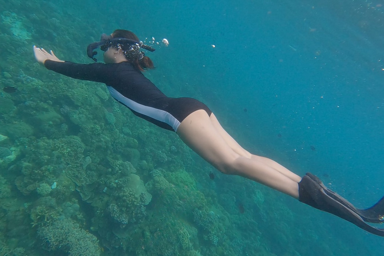 Woman swimming over various corals