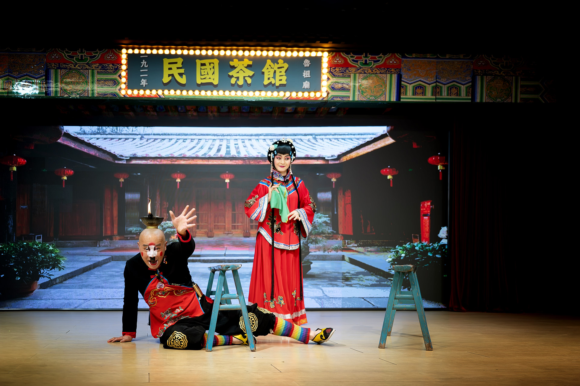 表演兼具趣味與技藝，演員們動作誇張且富有表現力，有的進行詼諧互動，有的展示高難度技巧，如頭頂燃具等，引得觀眾目光聚焦，背景呈現出古雅的中式庭院景象，搭配 “民國茶館” 的招牌，營造出濃郁的民國風情與傳統氛圍