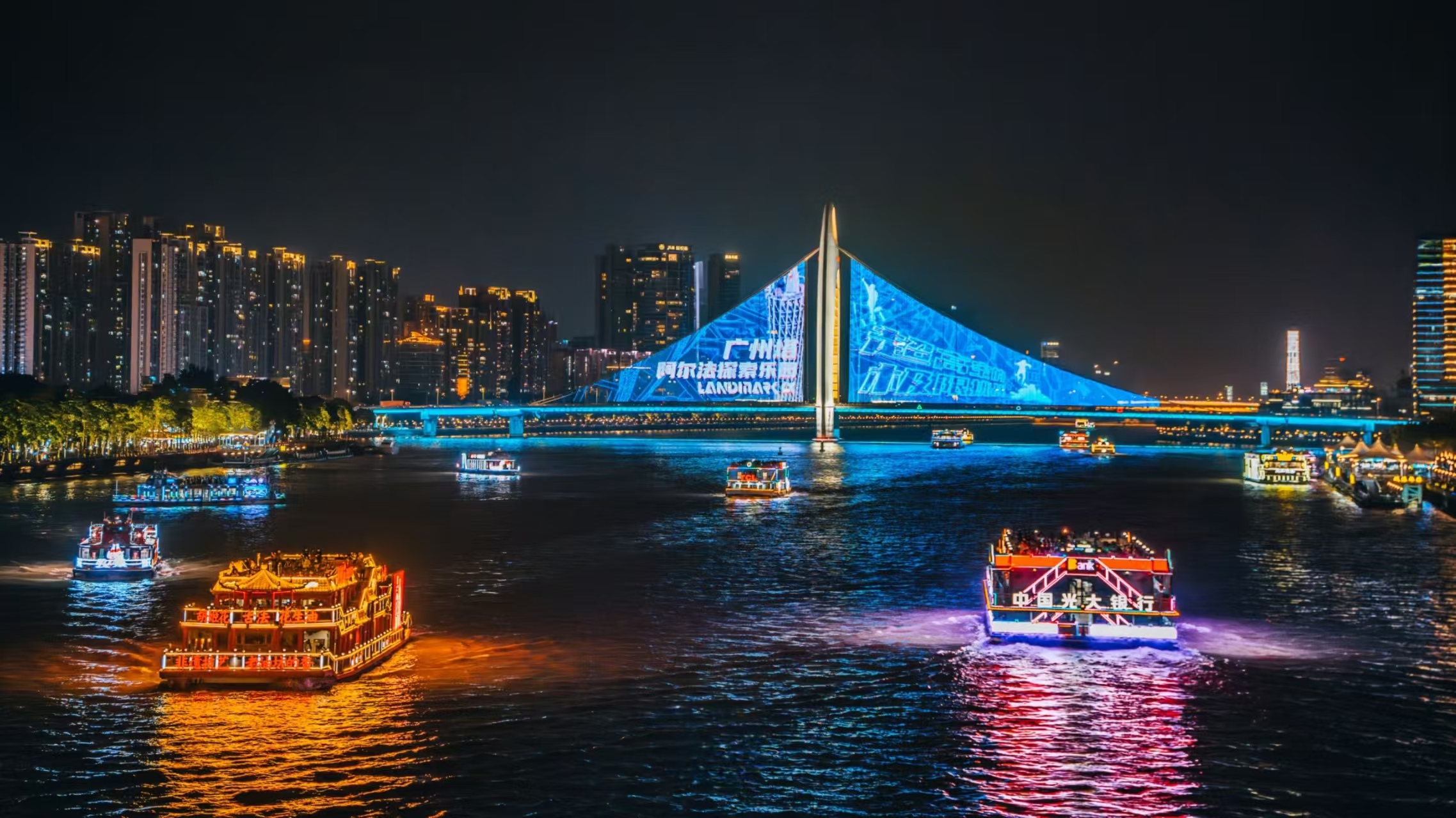 獵德大橋燈光秀現場:橋身投影廣告與藍調燈光呼應,多艘遊船滿載遊客遊弋江面,古今風格遊船與現代橋景碰撞出獨特夜韻 獵德大橋燈光秀現場:橋身投影廣告與藍調燈光呼應,多艘遊船滿載遊客遊弋江面,古今風格遊船與現代橋景碰撞出獨特夜韻