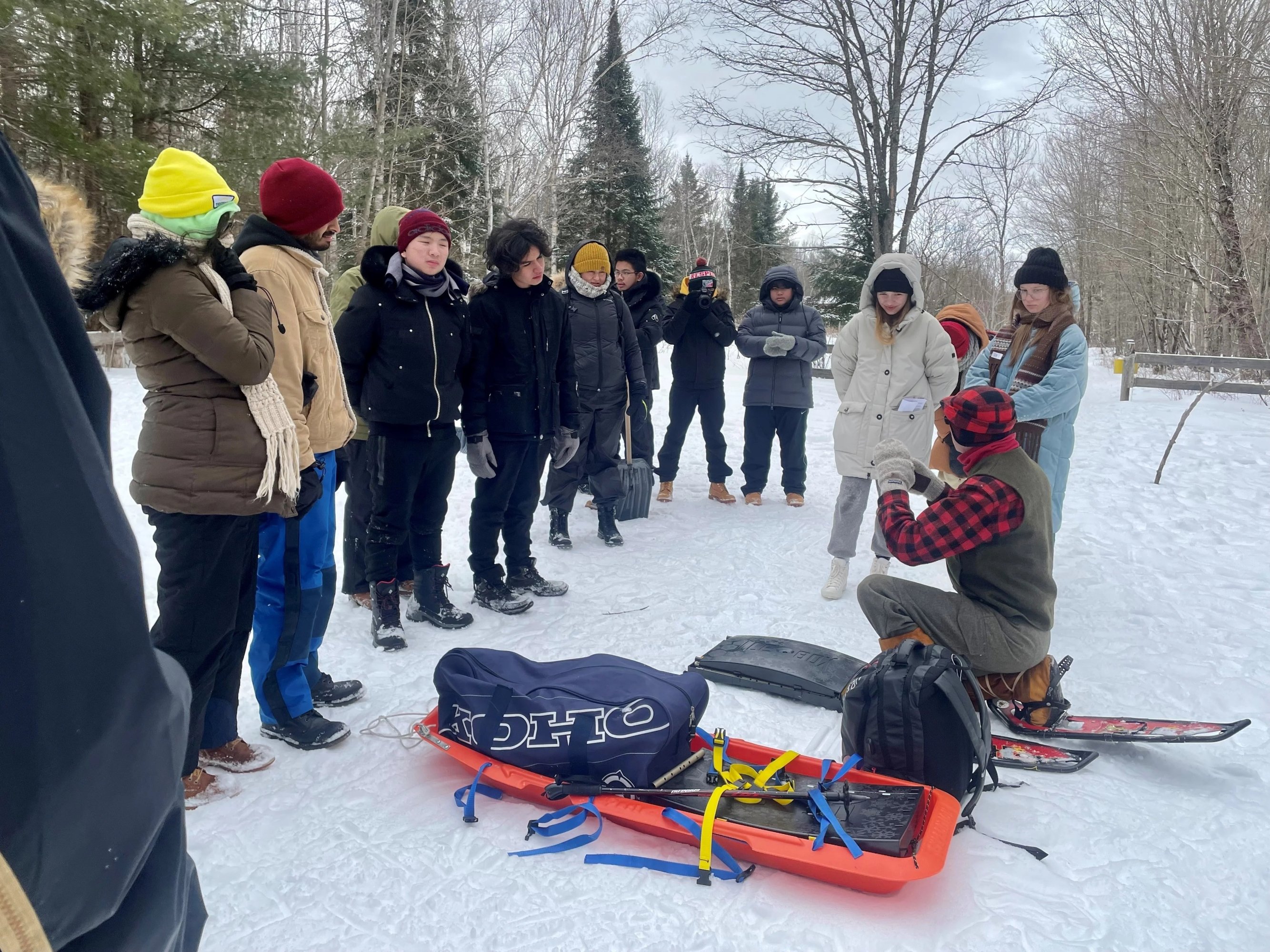 A small group gathers around the guide to learn the traditional igloo construction sequence
