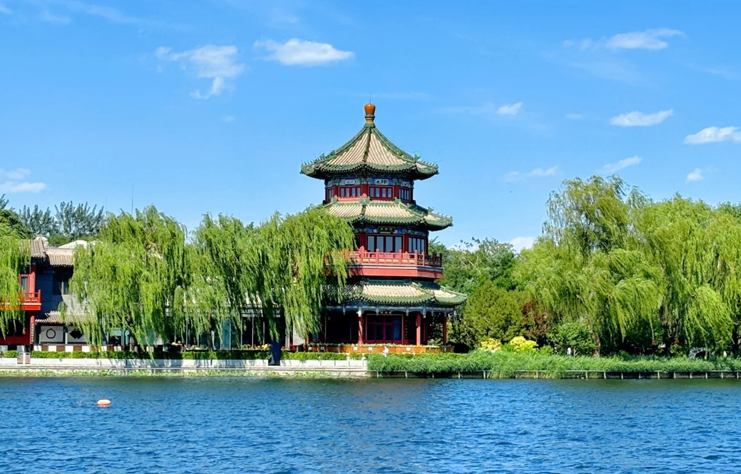 後海望海樓立於碧波之上，三重簷攢尖頂造型典雅，紅柱金頂在藍天綠樹間格外亮眼，柳絲輕拂，盡顯京城水榭的雅緻韻味