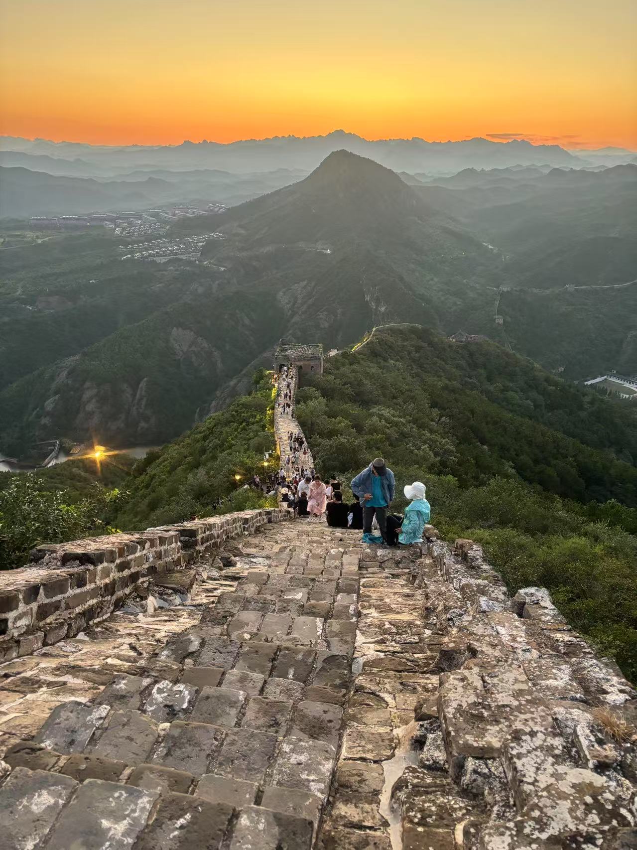 As the sun begins its descent, prepare to witness a truly spectacular sunset. The warm, orange glow of the setting sun bathes the Great Wall in a magical light, transforming the scene into a mesmerizing display of beauty.