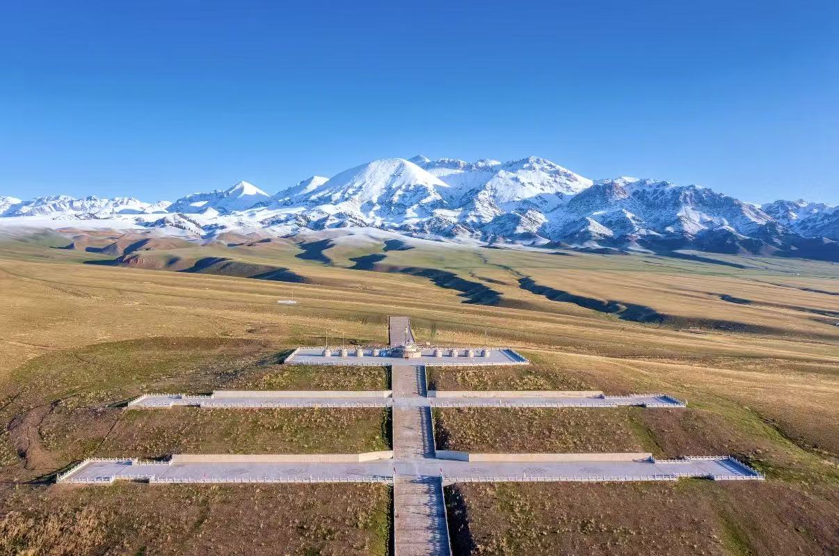 俯瞰視角下，賽里木湖點將臺的階梯式廣場直通向雪山，廣袤草原鋪展在兩側，雪嶺連綿，藍天澄澈，盡顯大氣磅礴的西域風光
