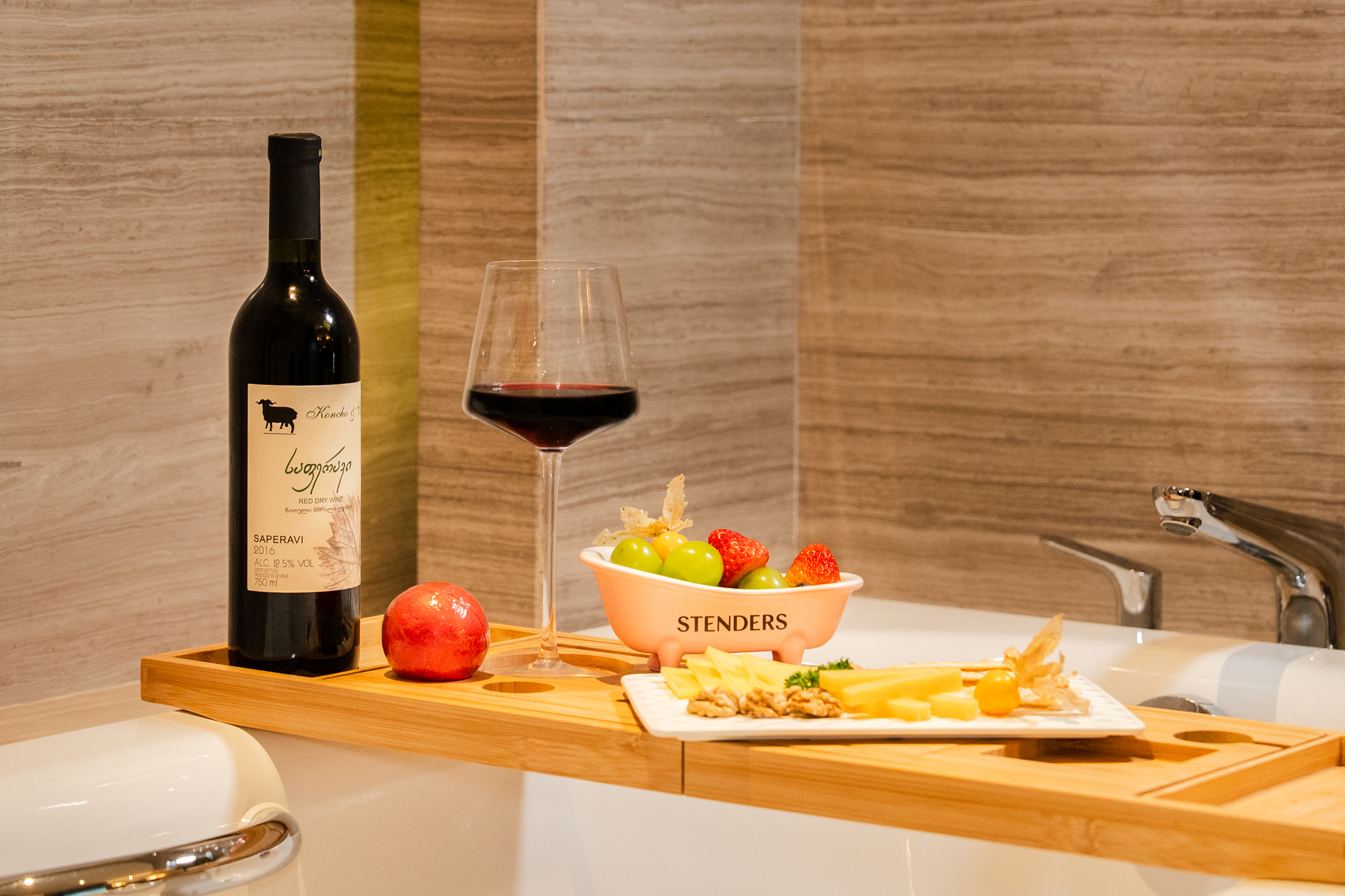 A bottle of red wine plus a cheese and fruit platter.