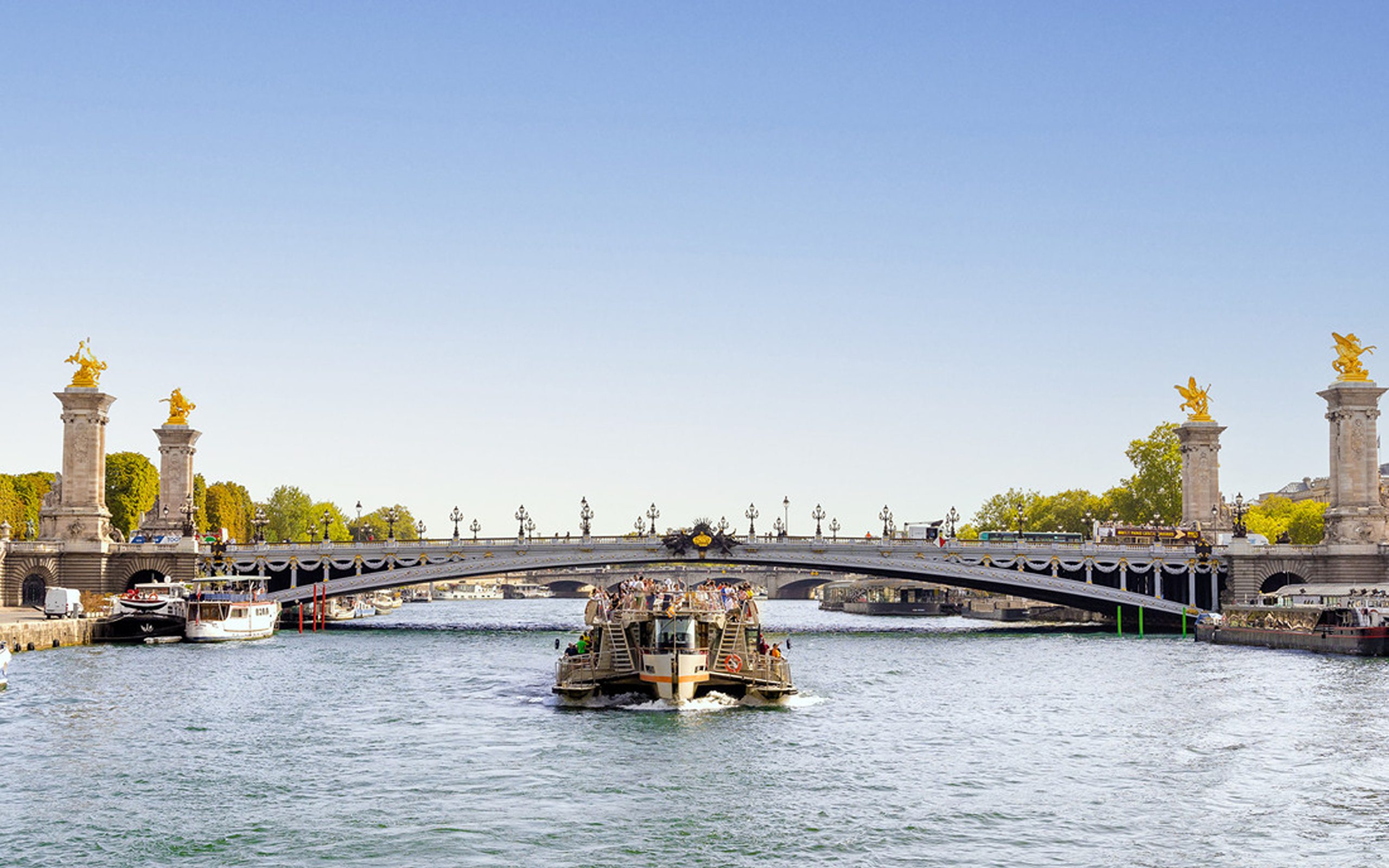 當兩艘 Bateaux Parisiens 遊船交會時，駛近亞歷山大三世橋的華麗拱門。