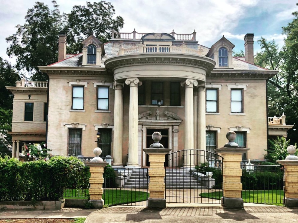Gated celebrity estate hidden behind lush greenery and ornate wrought-iron entrance gate