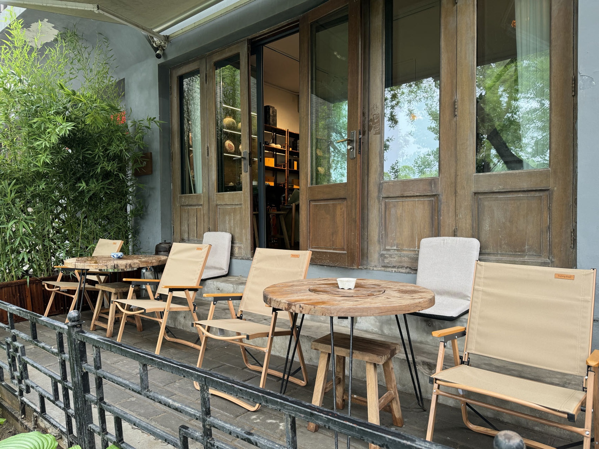 茶舍外休閒區，木桌摺椅，臨窗近綠，是品茶小坐的好地方