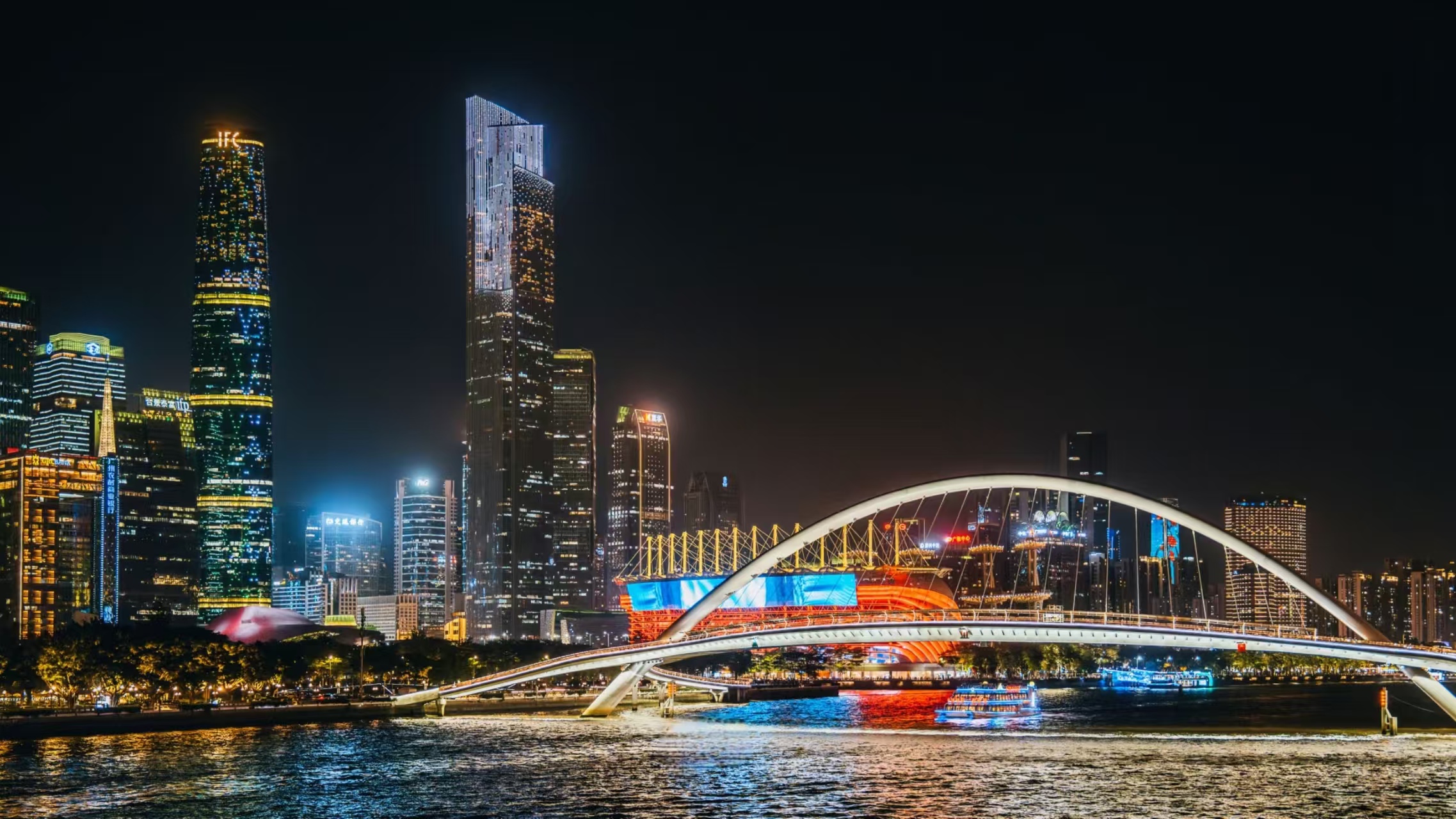 海心橋與城市天際線:流線型橋身串起兩岸燈火,遊船從橋下穿行,後方摩天樓群中 IFC 等建築燈光璀璨,現代建築與江景融合成畫 海心橋與城市天際線:流線型橋身串起兩岸燈火,遊船從橋下穿行,後方摩天樓群中 IFC 等建築燈光璀璨,現代建築與江景融合成畫