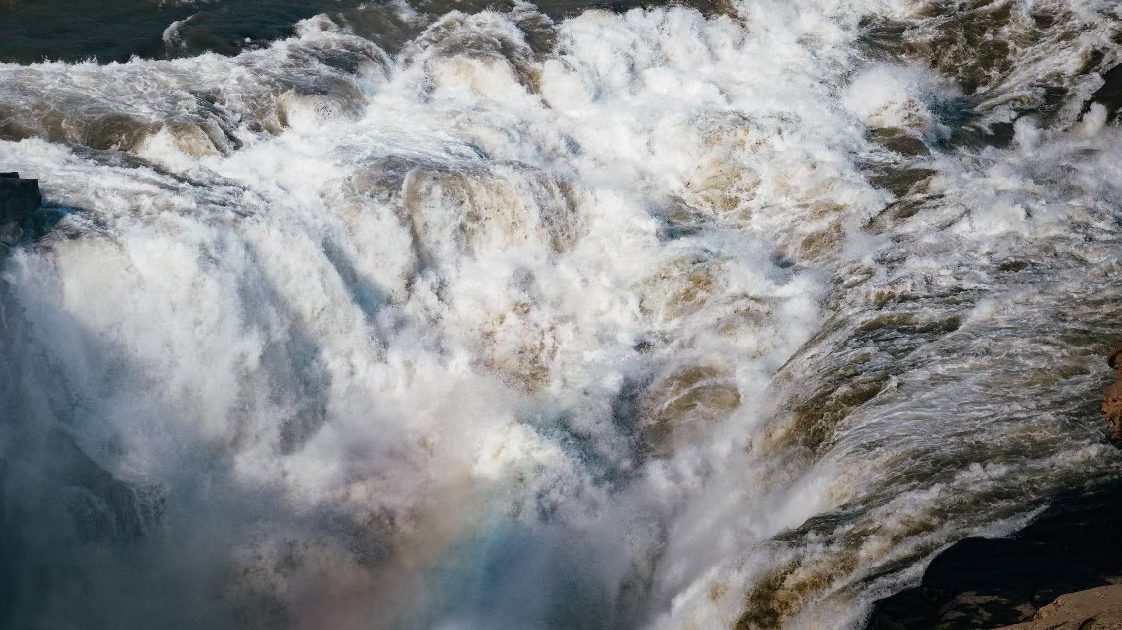 汛期壺口巨浪翻湧，渾濁黃河水層層跌落，千萬道激流撞擊岩石炸開漫天白浪，水流裹挾泥沙奔湧而下，水勢洶湧磅礴，盡顯黃河奔騰咆哮、雄渾豪邁的氣魄