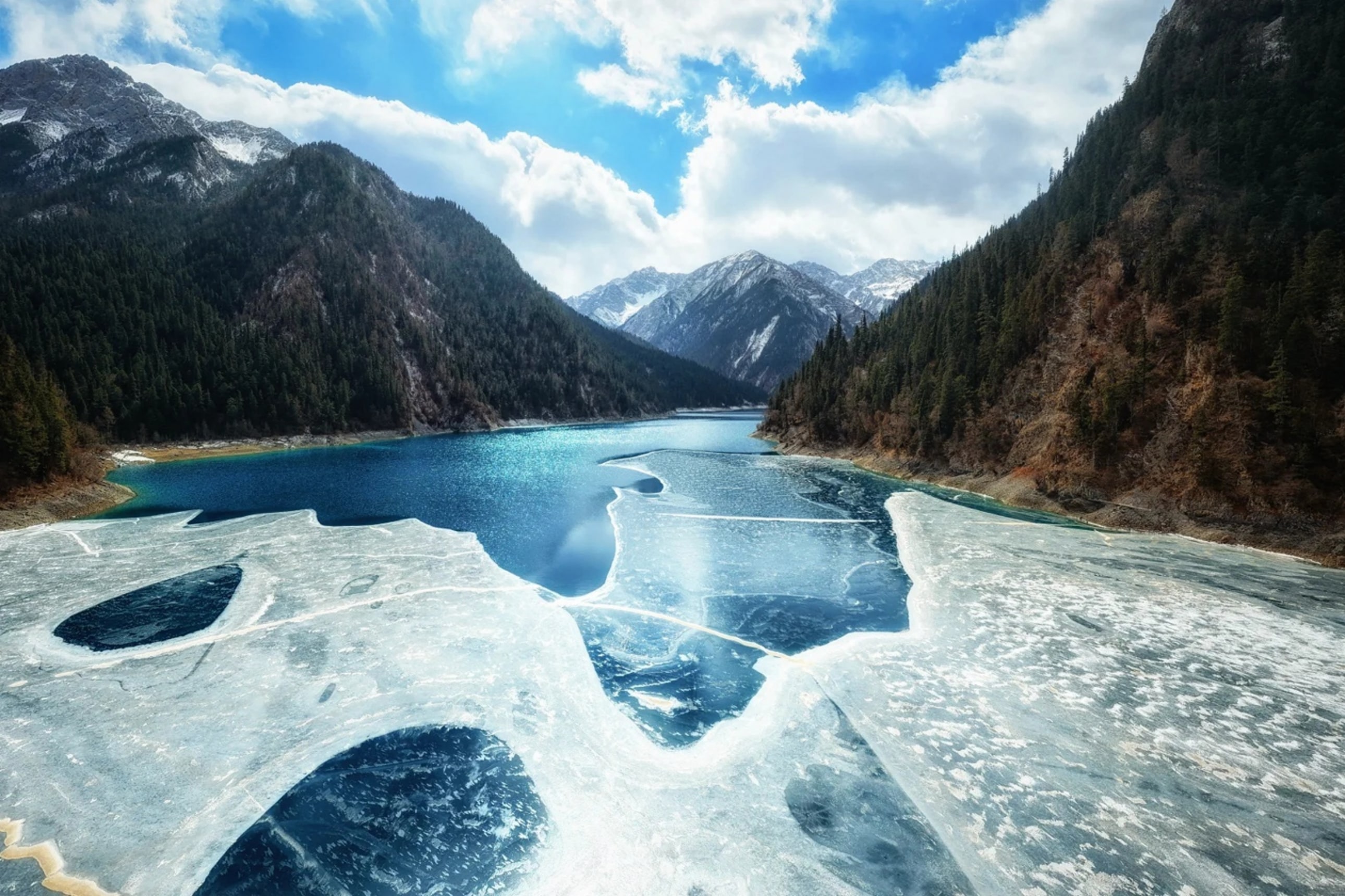九寨溝冬季湖景別具韻味，長海部分結冰，藍色水域與潔白冰雪交相輝映，遠處雪山與山谷構成壯麗的冬日景觀