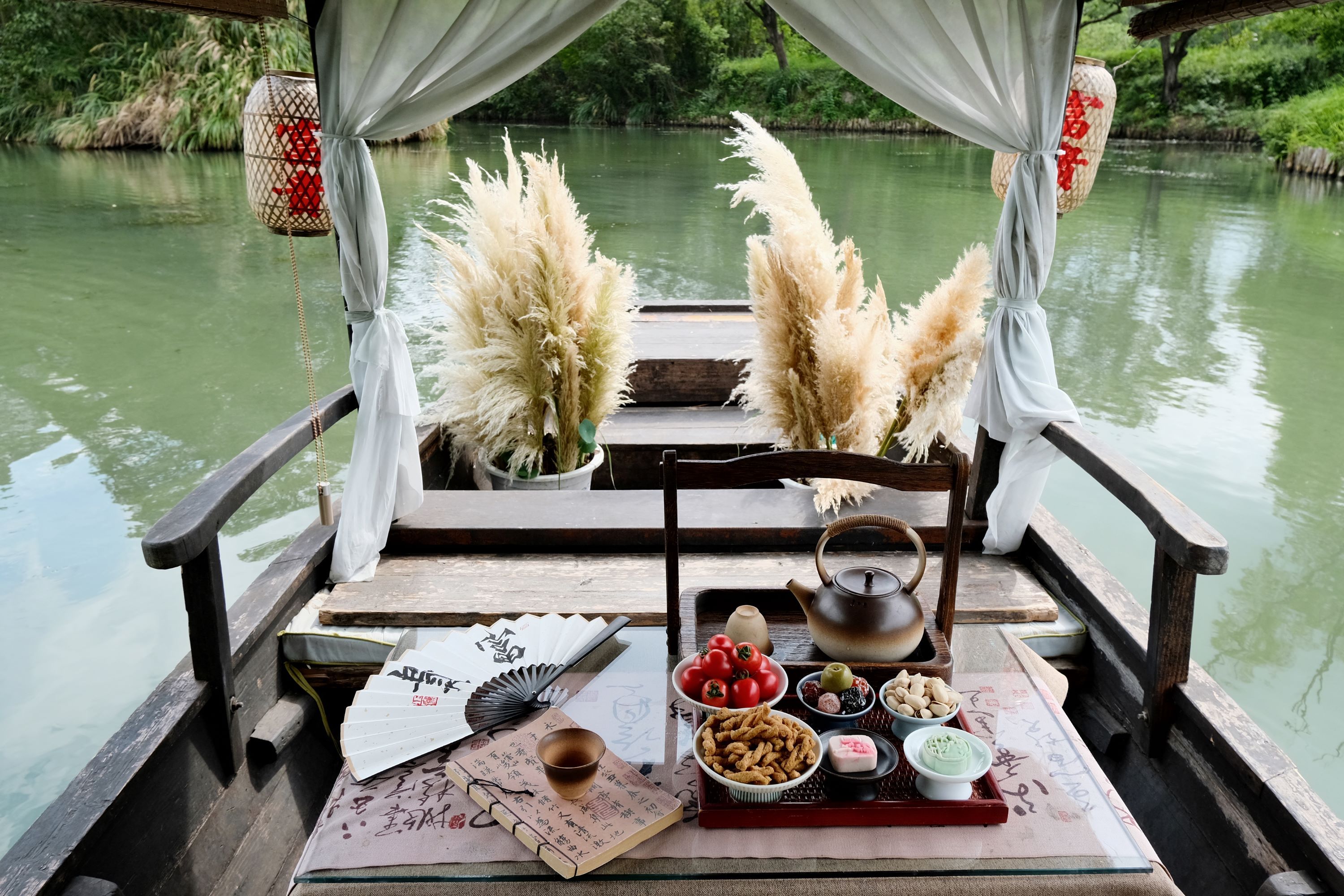 小船內佈置精巧,茶具、點心、摺扇等陳設其間,蒲葦裝飾增添自然意趣,窗外綠水悠悠,彷彿能讓人盡享水鄉慢生活的閒適 小船內佈置精巧,茶具、點心、摺扇等陳設其間,蒲葦裝飾增添自然意趣,窗外綠水悠悠,彷彿能讓人盡享水鄉慢生活的閒適