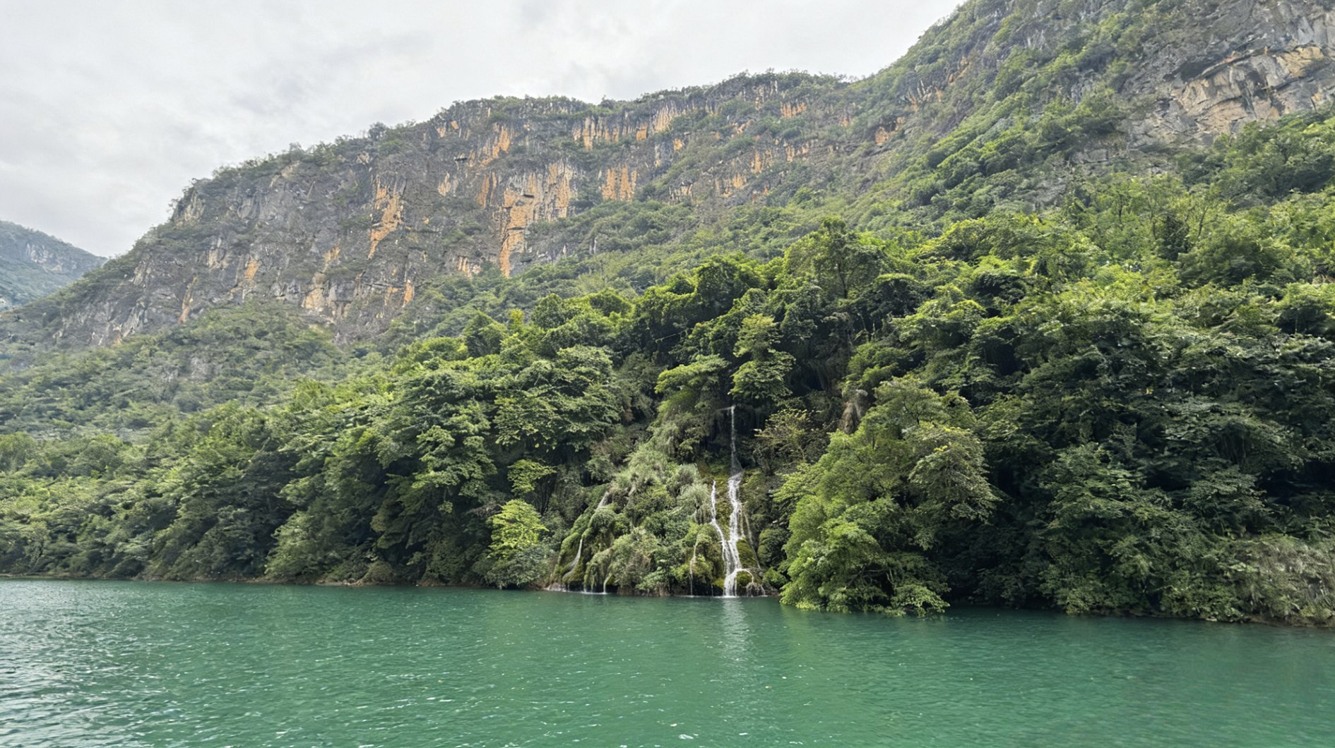 崖壁的褶皺裡,瀑布像銀線從濃蔭間垂落,碎成玉珠落進水裡 崖壁的褶皺裡,瀑布像銀線從濃蔭間垂落,碎成玉珠落進水裡