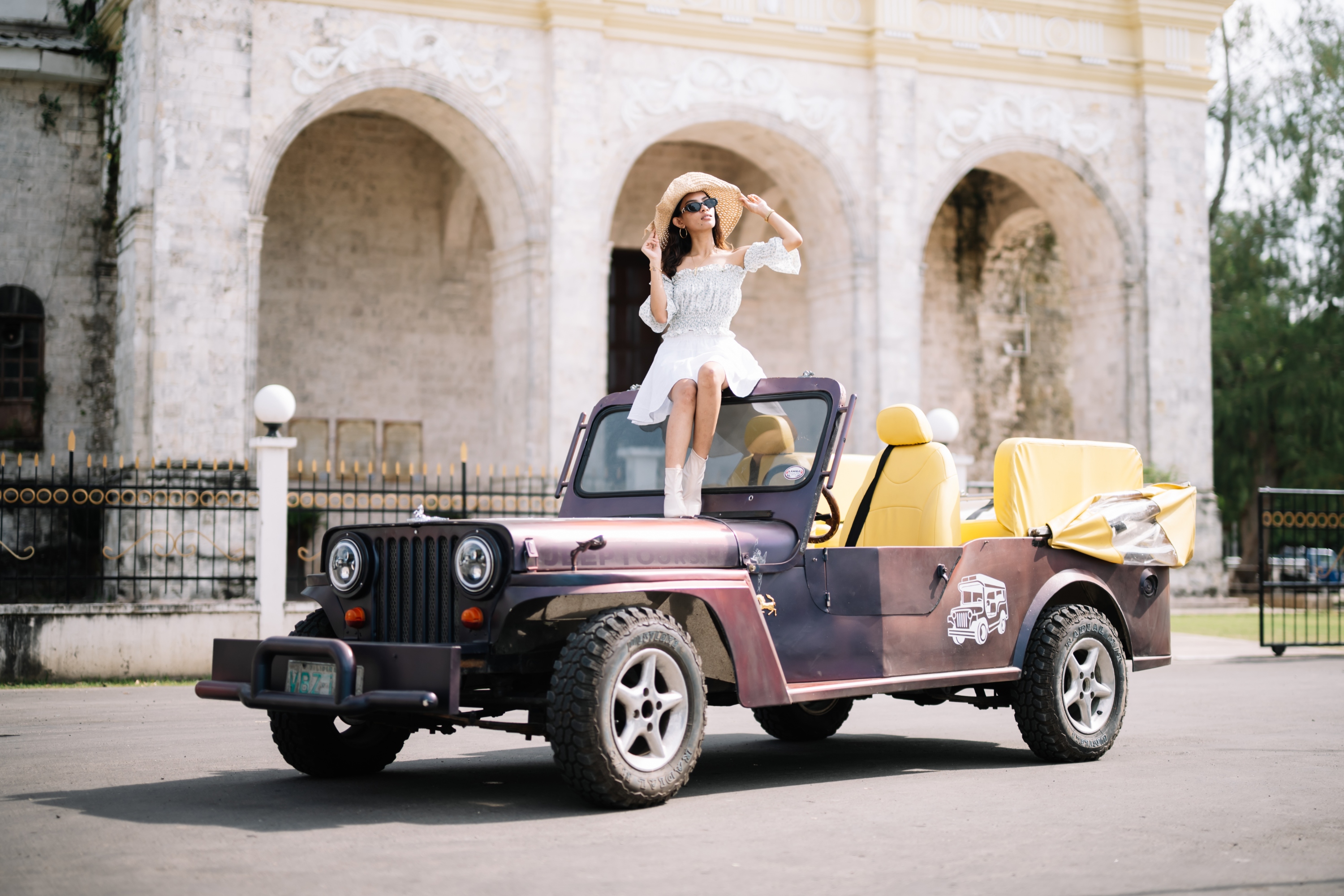 Woman enjoying the weather while sitting on the hood of a jeep