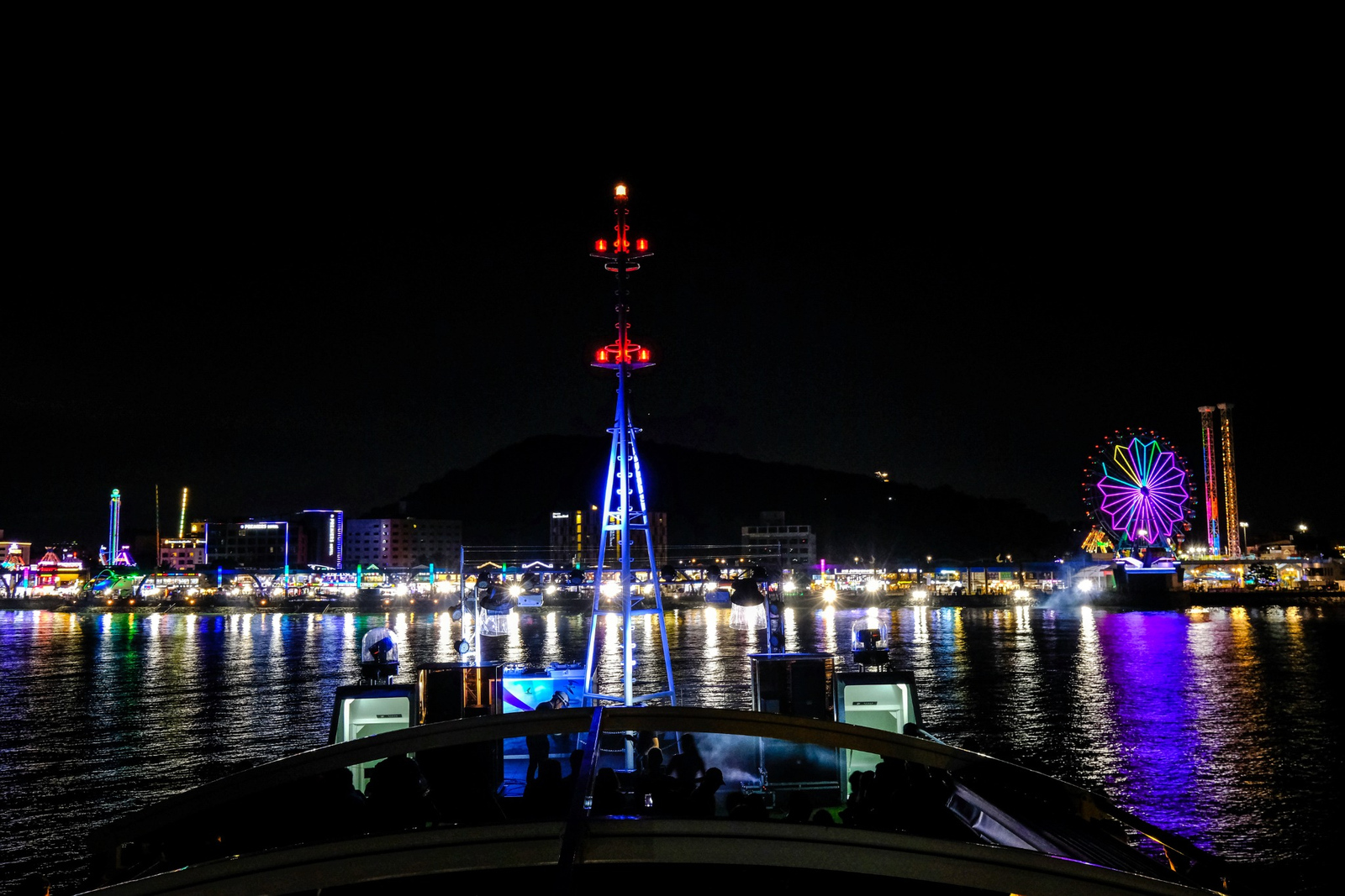 從遊輪上欣賞月尾島（Wolmido）迷人的夜景，五光十色的海濱燈光與標誌性的摩天輪在水面上交織出美麗的倒影。