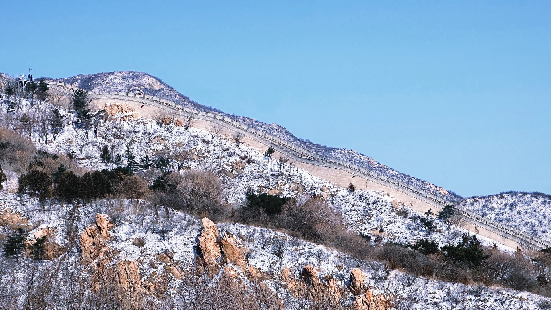 藍天之下，八達嶺長城在覆著薄雪的山巒間蜿蜒延伸，勾勒出冬日裡蒼茫壯闊的北國風光。