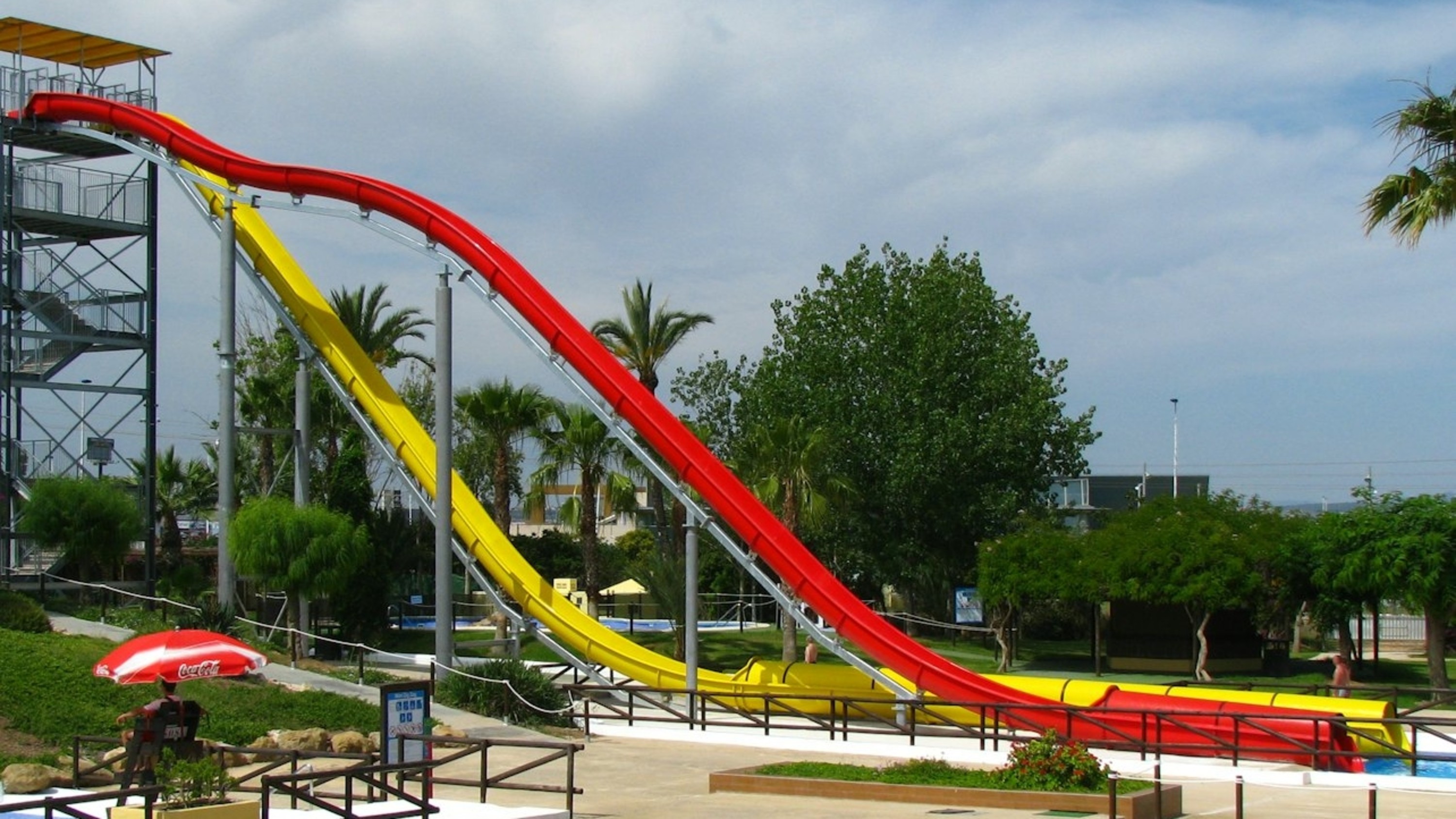 Tall, vibrant yellow and red slides twist high into the sky, inviting daring riders