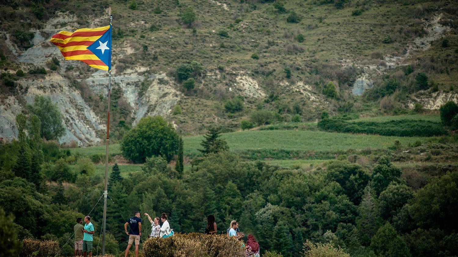 A view of Tavertet village nestled among lush greenery, with cliffs in the background