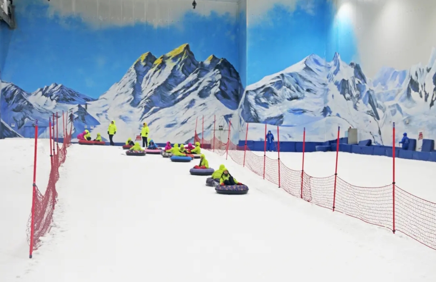 雪場中,人們坐在色彩各異的雪圈上,從雪道上滑下 雪場中,人們坐在色彩各異的雪圈上,從雪道上滑下