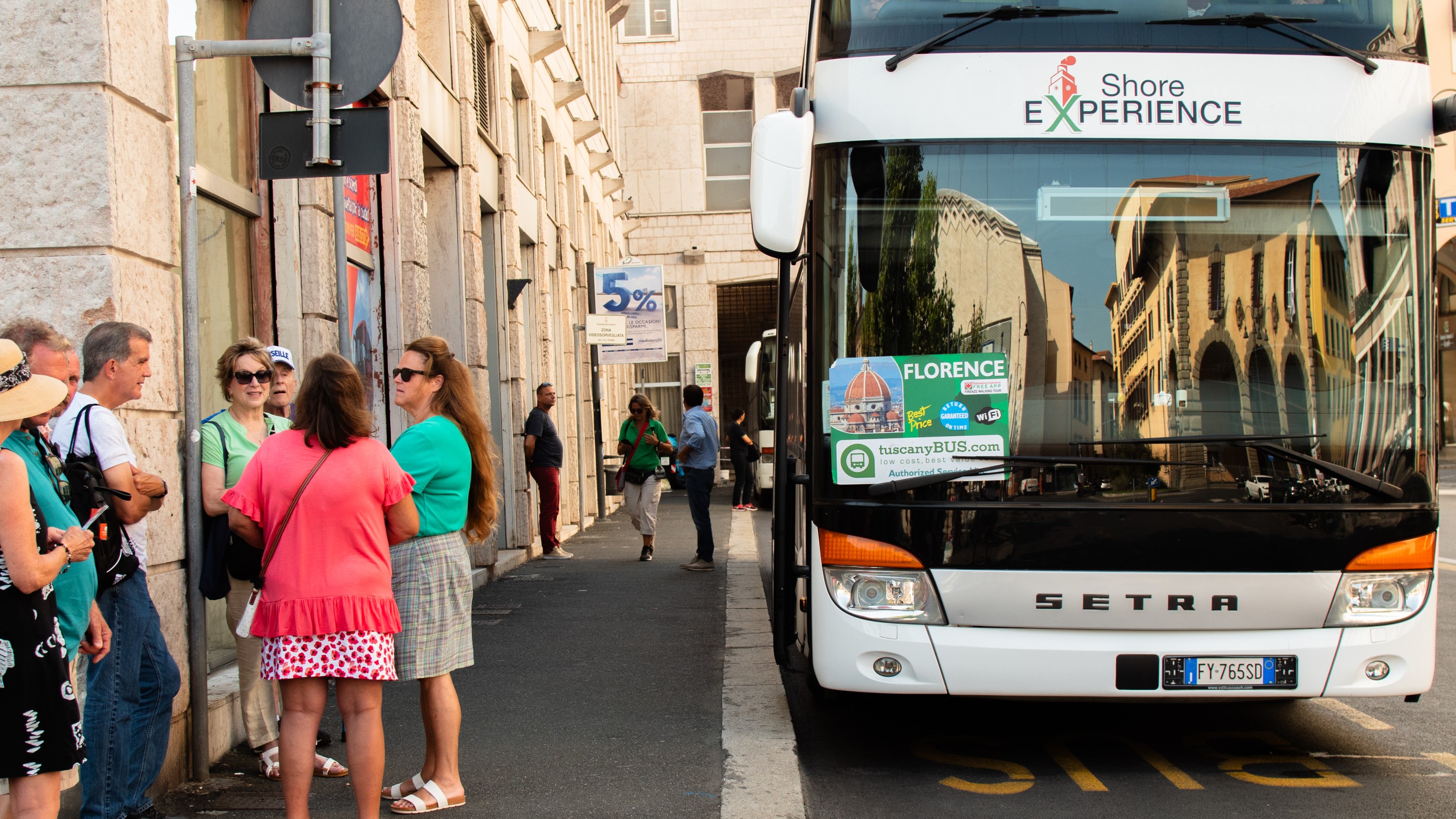 Bus parked with people gathered outside, chatting and preparing to board for their tour