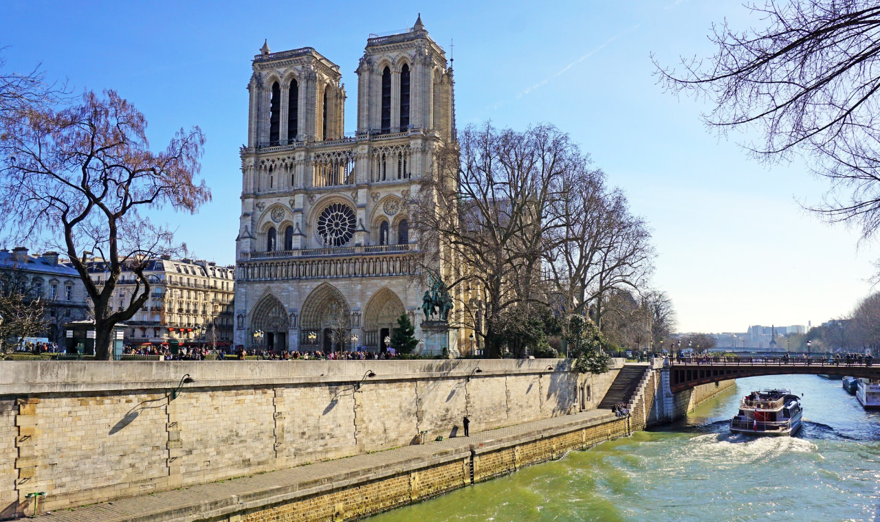 河邊的巴黎聖母院,鄰近橋樑,一艘小船在下方平靜地駛過 河邊的巴黎聖母院,鄰近橋樑,一艘小船在下方平靜地駛過