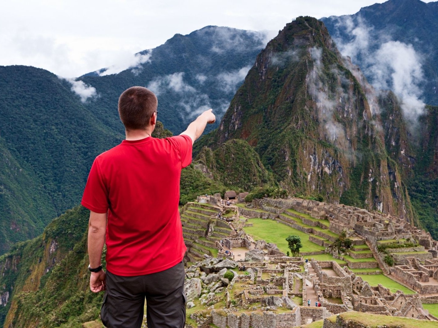 Tourist admiring the dramatic Machu Picchu landscape.