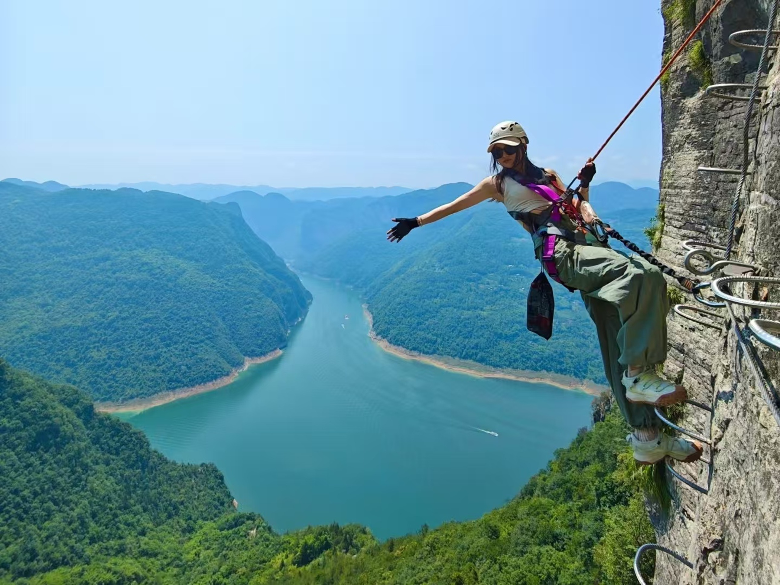 展臂後仰，碧江穿峽而過，風裹著衣襬，把懸崖挑戰變成與山河同框的鬆弛 “寫真時刻”