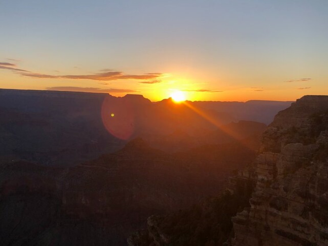 Witness a magical Grand Canyon sunrise casting golden hues over the vast canyon rim