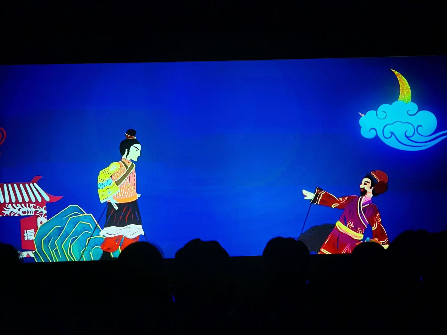 深藍幕布襯著彎月祥雲,兩位古裝皮影人物對峙,色彩濃烈,充滿川派皮影的戲劇張力 深藍幕布襯著彎月祥雲,兩位古裝皮影人物對峙,色彩濃烈,充滿川派皮影的戲劇張力