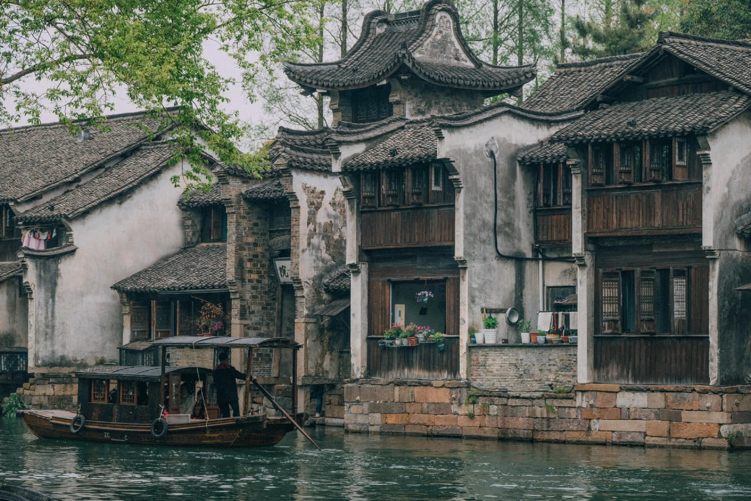 臨水古建錯落有致，木窗黛瓦韻味十足。烏篷船輕倚岸邊，綠樹掩映間，把江南古鎮的雅緻與菸火氣，完美定格