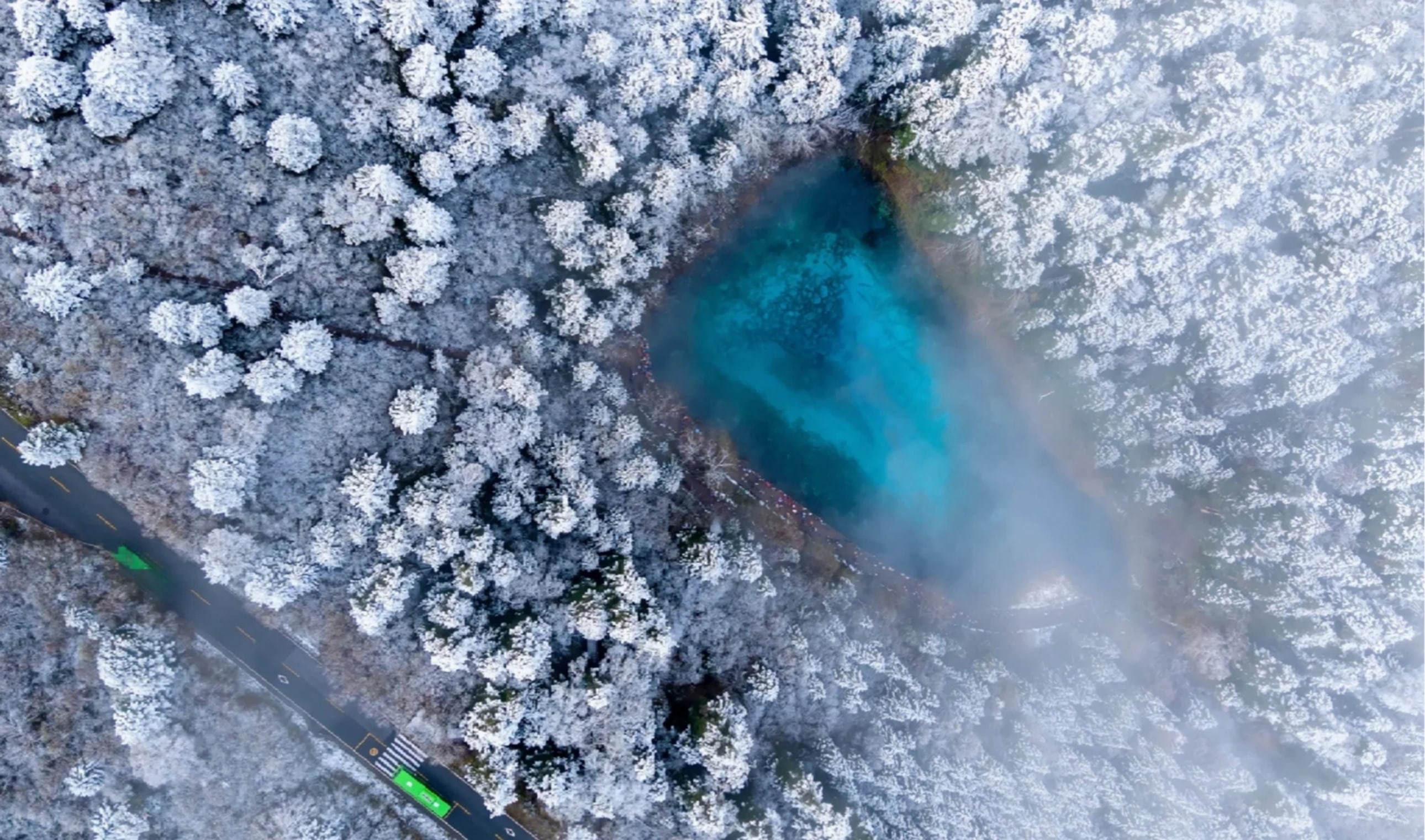 九寨溝冬日湖景宛如仙境，湛藍湖泊被皚皚白雪與層層森林環繞，薄霧輕籠山間，營造出靜謐夢幻的氛圍