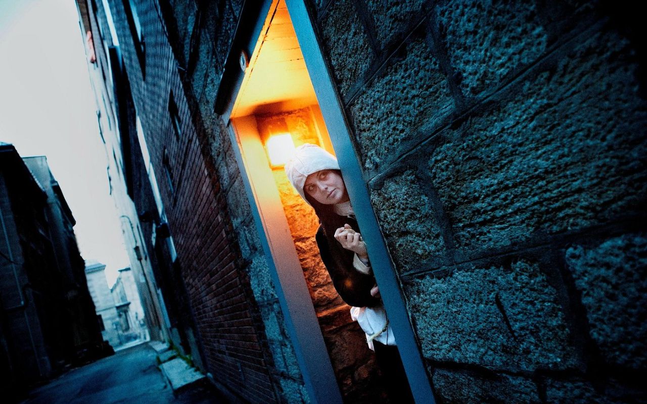 在舊蒙特婁夜間徒步之旅中，一位鬼故事導遊從狹窄的小巷中現身。