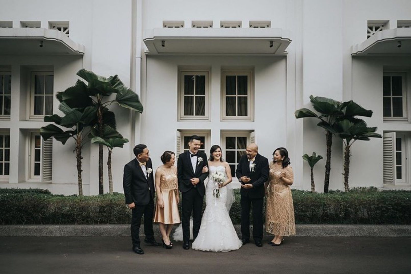 Bride, groom, and family standing outside white house
