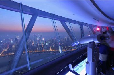 傍晚時分，城市燈光漸亮，黃浦江對岸的建築燈火璀璨，觀景臺內的望遠鏡可供遊客眺望