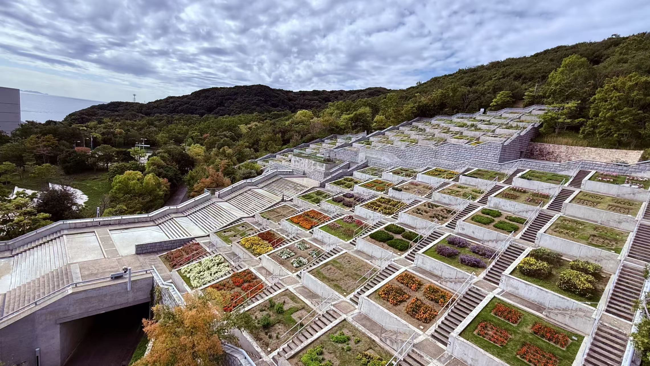 秋天的百段苑，如同調色盤般綻放層層暖意，金黃、深紅與橙褐交織出一幅立體的季節畫卷。 在安藤忠雄的幾何花壇間漫步，每一步都沉浸在秋色的詩意與自然的律動之中。