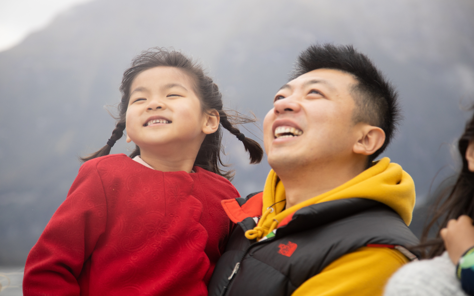 幸福的一家人正在欣賞米爾福德峽灣壯麗的景色，周圍環繞著高聳的懸崖和傾瀉而下的瀑布