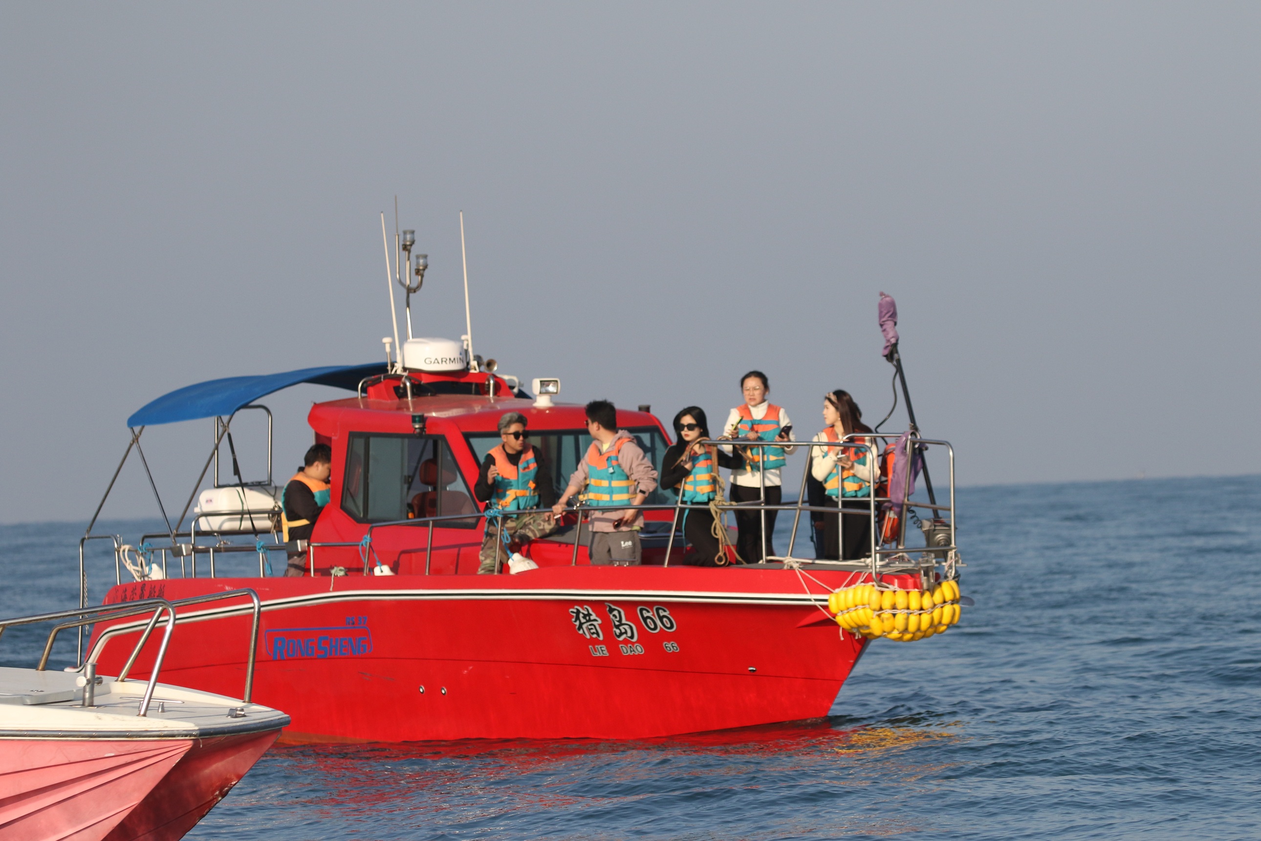 湛藍海面泛著粼粼波光,遊船停駐於斜陽島附近海域,遊客舉著長焦相機凝神眺望 湛藍海面泛著粼粼波光,遊船停駐於斜陽島附近海域,遊客舉著長焦相機凝神眺望