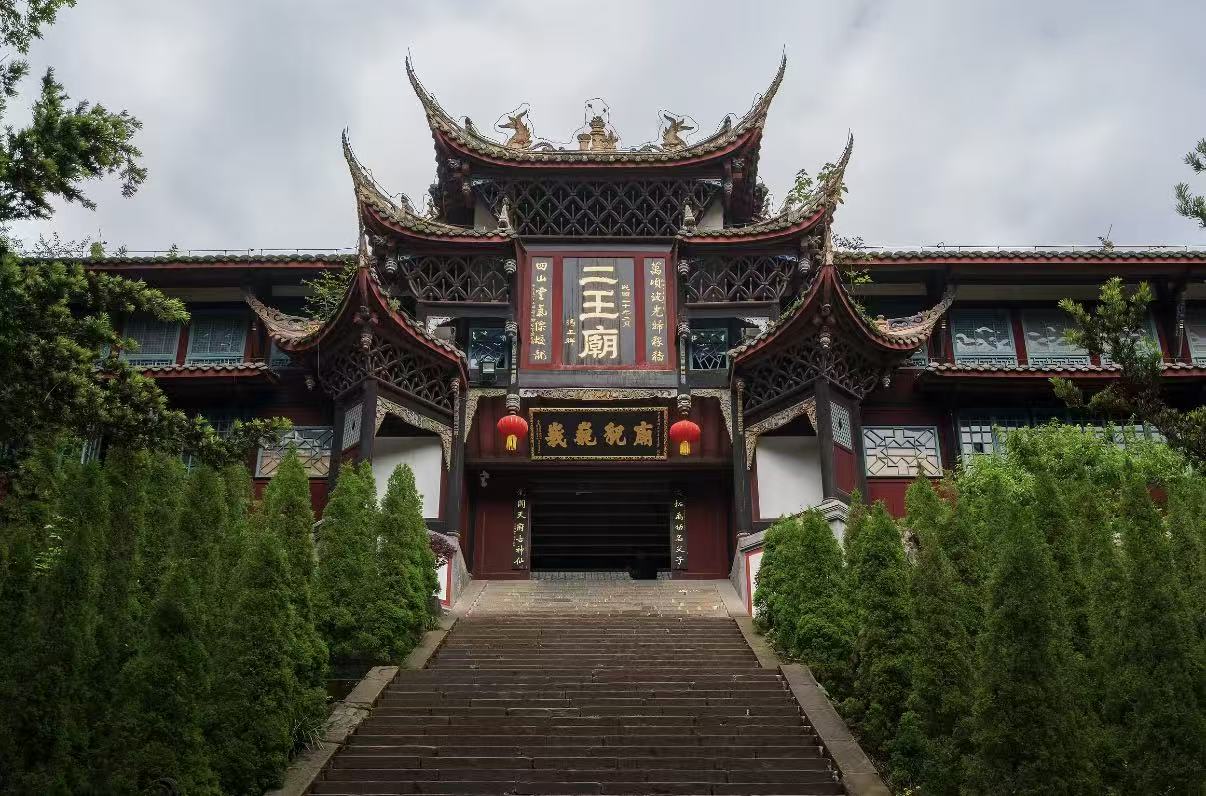 都江堰二王廟山門莊重典雅,飛簷翹角飾有瑞獸,黑底金字匾額醒目,紅牆木構配兩側翠柏,石階引向殿宇,盡顯川西古建的肅穆古韻 都江堰二王廟山門莊重典雅,飛簷翹角飾有瑞獸,黑底金字匾額醒目,紅牆木構配兩側翠柏,石階引向殿宇,盡顯川西古建的肅穆古韻