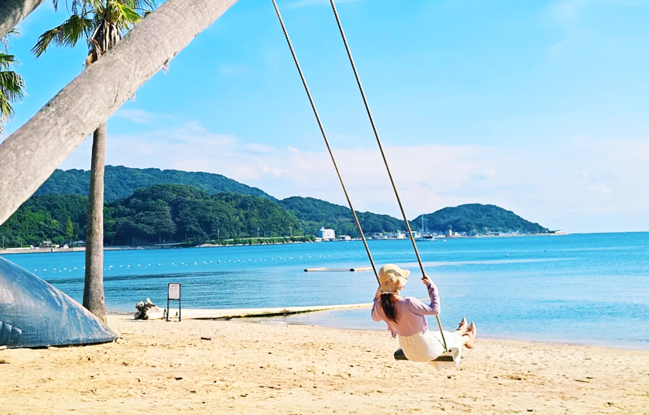 糸島海岸的人氣打卡點,兩棵椰子樹間懸掛木質鞦韆。面朝碧海藍天,坐在鞦韆上可感受海風拂面,彷彿置身南國樂園,是社交媒體上備受追捧的浪漫攝影地。 糸島海岸的人氣打卡點,兩棵椰子樹間懸掛木質鞦韆。面朝碧海藍天,坐在鞦韆上可感受海風拂面,彷彿置身南國樂園,是社交媒體上備受追捧的浪漫攝影地。